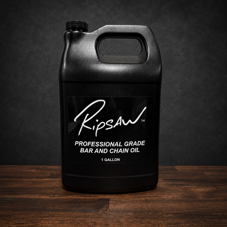 A black plastic 1-gallon jug of Ripsaw Professional Grade Bar and Chain Oil, displayed on a dark wooden surface against a dark textured background.